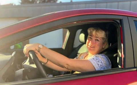 Fahrlehrerin Tanja am Steuer eines roten Fahrschulautos